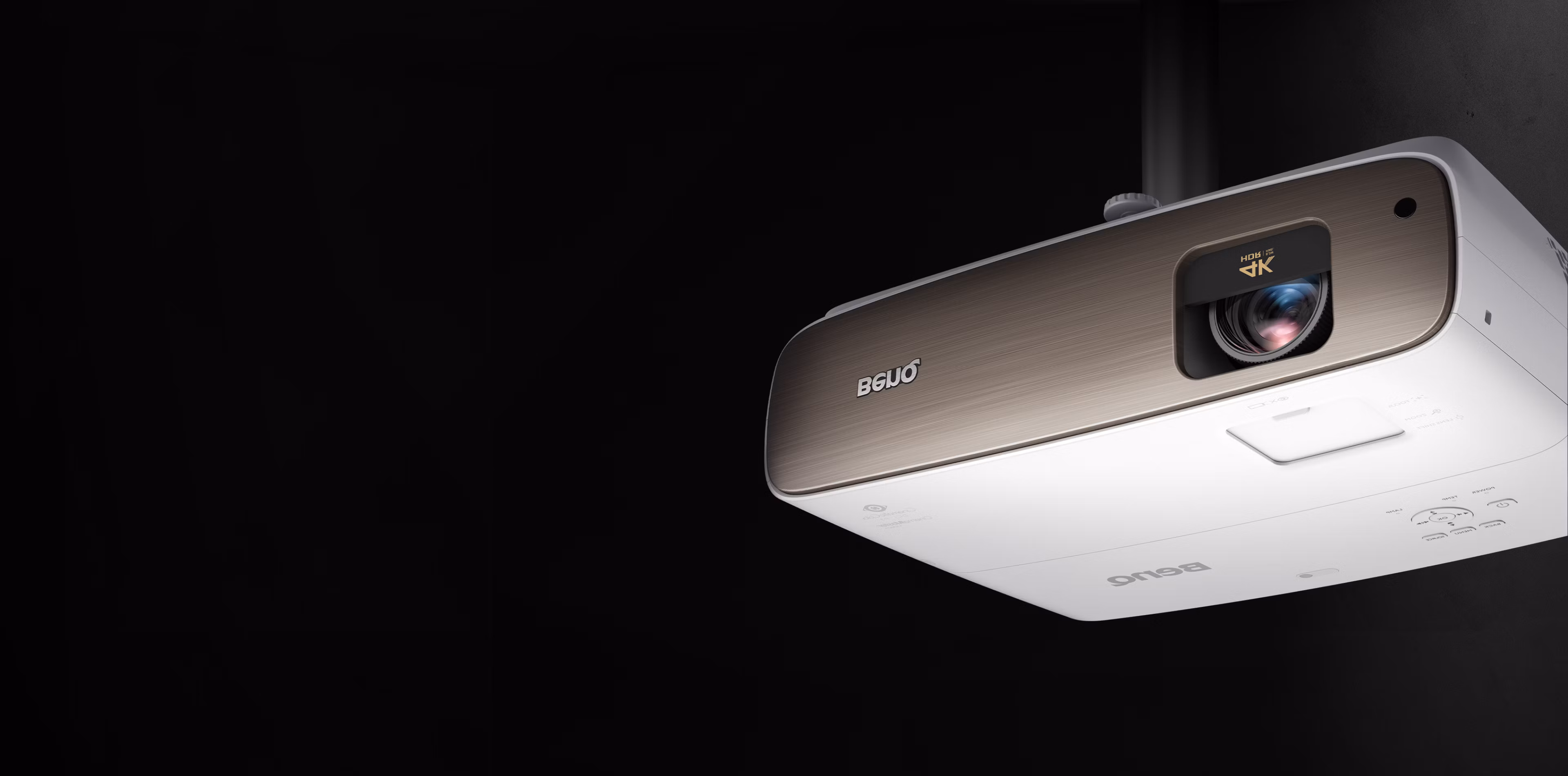 BenQ HT3550 projector from below at an angle, brushed bronze front panel with 4K HDR lens badge, on a black background