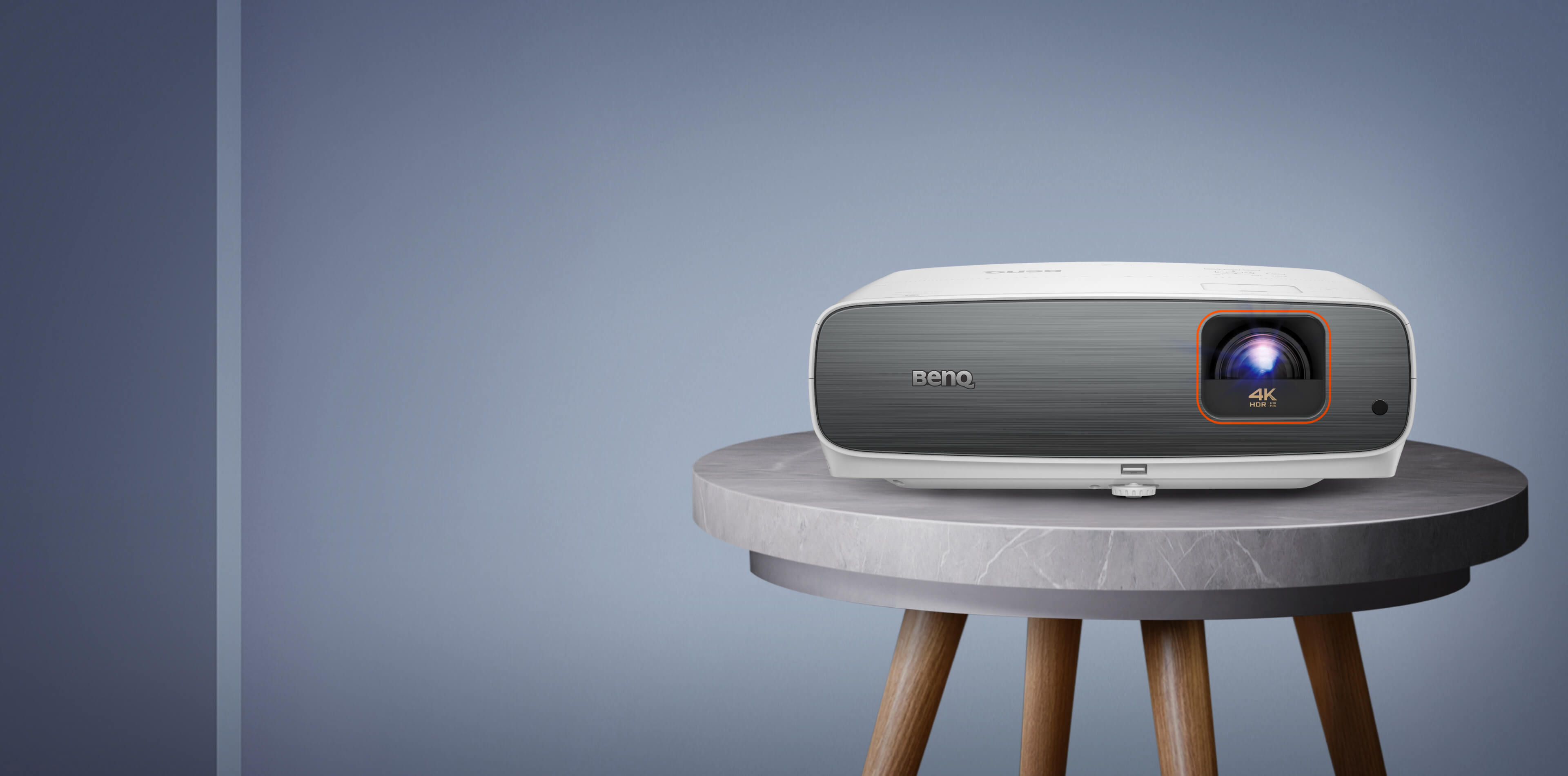 BenQ TK860i front view on a round marble side table: white body with a grey brushed front panel and the lens at upper right marked 4K HDR